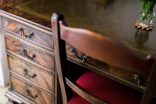 a wooden dresser with a red chair next to it at Burkleigh House in Johannesburg