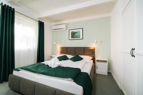 ein Schlafzimmer mit einem großen Bett und einer grünen Decke in der Unterkunft Topáz Apartmanházak in Balatongyörök
