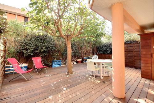 um pátio com cadeiras, uma mesa e uma árvore em Appartement confortable dans une résidence à 50m de la plage em Valras-Plage
