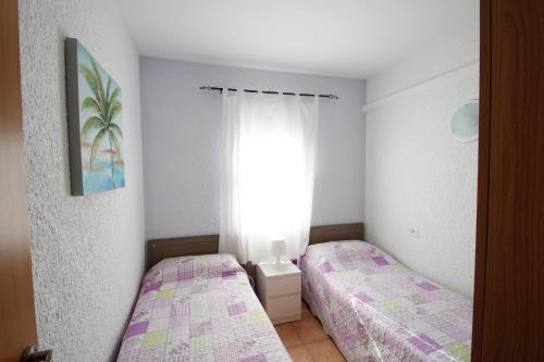 2 camas en una habitación pequeña con ventana en Casas Blancas 37, en Miami Platja