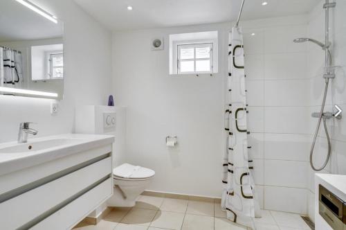 a white bathroom with a shower and a toilet at 1 Skøn og lyst indrettet feriehus i Skagen in Skagen