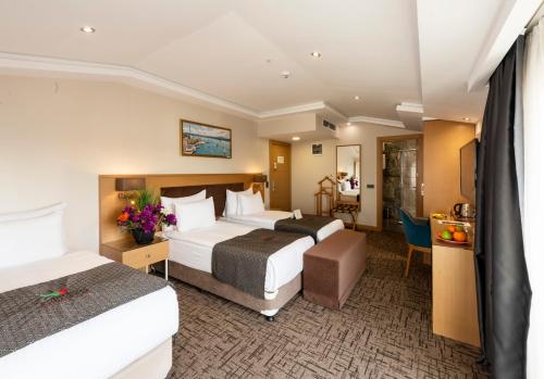 a hotel room with two beds and a desk at Hotel Boursier 2 & Spa in Istanbul