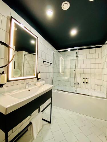 a bathroom with a sink and a tub and a mirror at Arche Hotel Krakowska in Warsaw