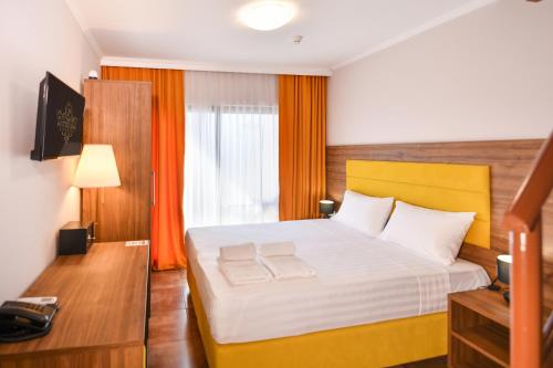 a bedroom with a large bed with orange curtains at Hotel Palladium Sithonia in Kalamitsi