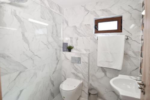 a white bathroom with a toilet and a sink at Hotel Palladium Sithonia in Kalamitsi