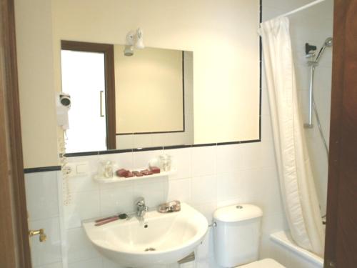 a bathroom with a sink and a mirror and a toilet at Hotel Villa del Son in Porto do Son