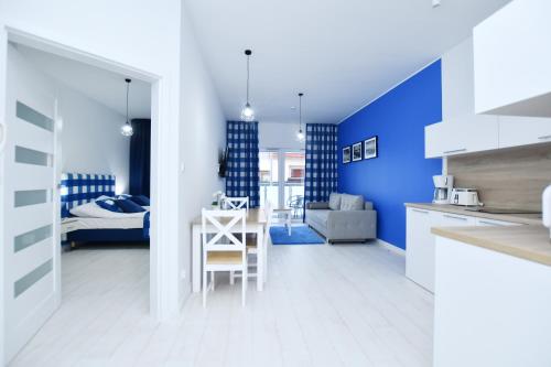 a kitchen and living room with a blue wall at Sunset Resort, Nadmorska 106 in Grzybowo