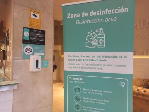 a sign for a disinfection sign in a store at Hotel Alda San Carlos in Santiago de Compostela