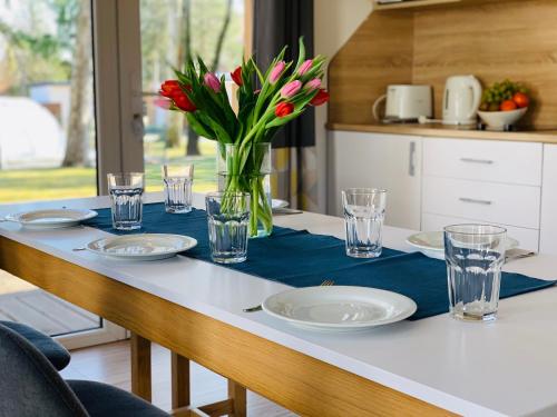 a table with plates and glasses and a vase of flowers at Barack Thermal & Natura Apartments in Tiszakécske