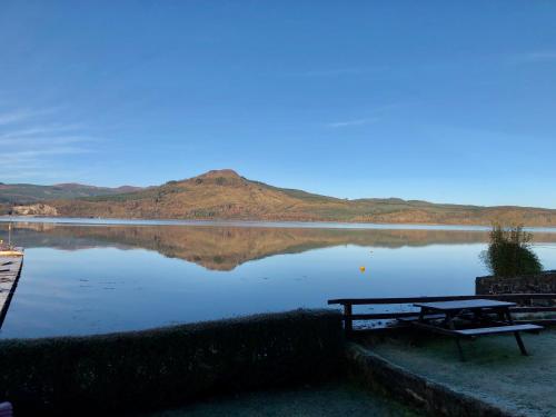 a lake with a picnic table and a bench at An Airigh in Cairndow