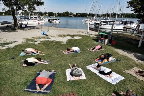 a group of people doing yoga on the grass near the water at Przystań Tło dla Mew in Rydzewo