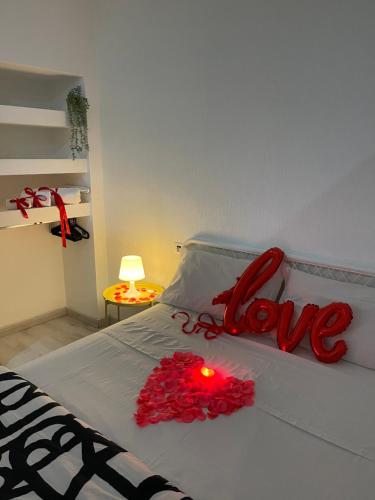 a bed with red roses and a love sign on it at Costantino Home in Pompei