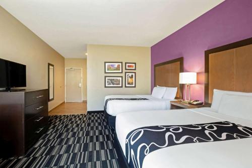 a hotel room with two beds and a flat screen tv at La Quinta by Wyndham Cedar City in Cedar City