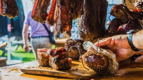 a person holding a table with meat on a cutting board at Przystań Tło dla Mew in Rydzewo