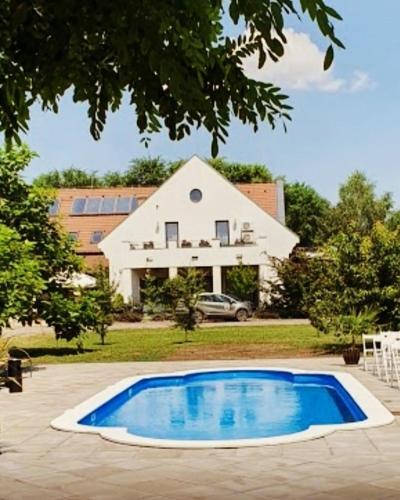 a large blue swimming pool in front of a house at Caballus Lovasmajor Panzió in Nyíregyháza