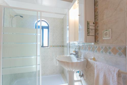 a white bathroom with a sink and a shower at Villa Misofia in Almancil