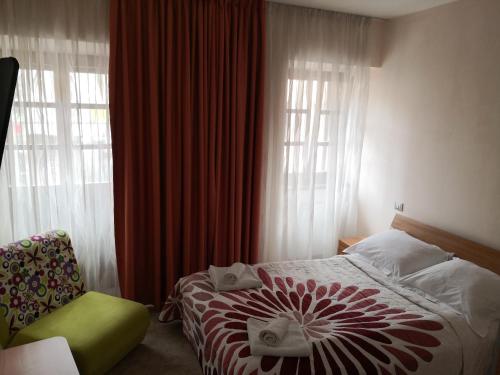 a bedroom with a bed and a chair and windows at Gostilna pri Dragici, gostilna s prenočišči, d.o.o. in Sežana
