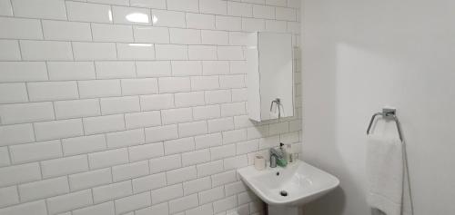 a white bathroom with a sink and a mirror at Garland Modern Apartment Tilbury with Parking in Tilbury