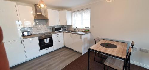 a kitchen with white cabinets and a wooden table at Garland Modern Apartment Tilbury with Parking in Tilbury
