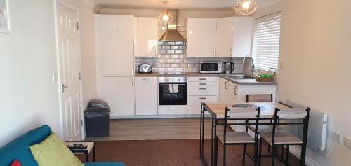 a kitchen with white cabinets and a table and chairs at Garland Modern Apartment Tilbury with Parking in Tilbury