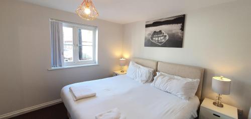 a bedroom with a bed with white sheets and a window at Garland Modern Apartment Tilbury with Parking in Tilbury