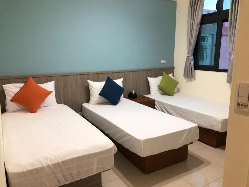 金寧鄉的住宿－熊寶貝民宿，客房设有三张床和色彩缤纷的枕头。