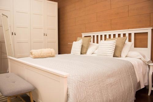 un letto bianco con cuscini bianchi e una sedia di LOFT CENTRO ALMERIA a Almería