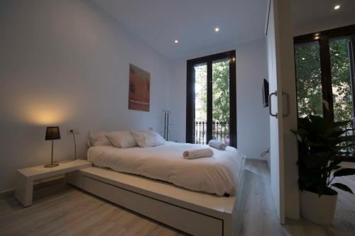 a white bedroom with a large bed with a bench at Roger De Lluria Design Apartment in Barcelona