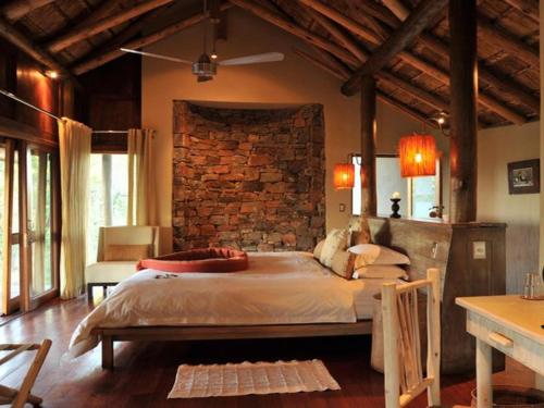 1 dormitorio con 1 cama grande y pared de ladrillo en Buffalo Ridge Safari Lodge, en Reserva de Madikwe