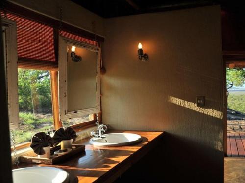 baño con 2 lavabos y ventana en Buffalo Ridge Safari Lodge, en Reserva de Madikwe