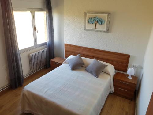 a bedroom with a large white bed with a window at Vivienda Turística El Asturiano in Montamarta