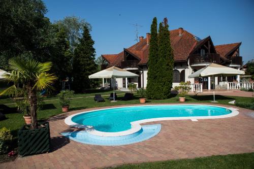 a swimming pool in front of a house at Zsanett Hotel in Balatonkeresztúr