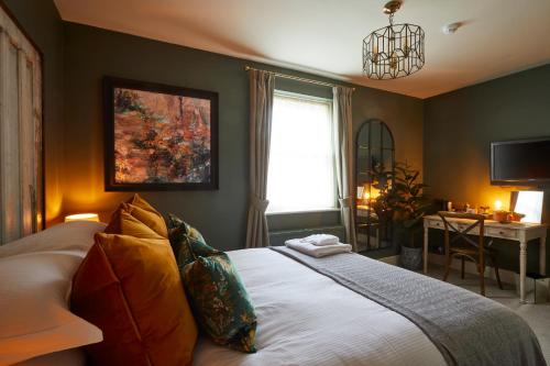 a bedroom with a bed and a desk and a window at The Quarrymans Arms in Corsham