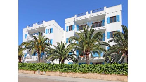 een wit gebouw met palmbomen ervoor bij Apartamentos Sema in Son Servera