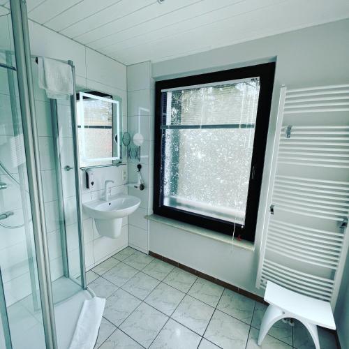 a white bathroom with a sink and a window at Appartement Seebadallee mit Klimaanlage und Wallbox für e-Autos in Rangsdorf