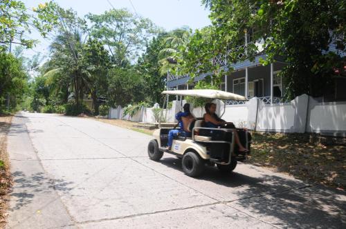 two people riding on a golf cart down a street at Coconut Paradise Lodge in San Andrés