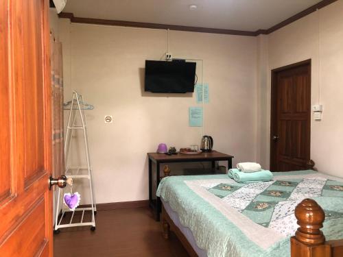 a bedroom with a bed and a television at Ruen Thai Ban Rim Nam in Kamphaeng Phet