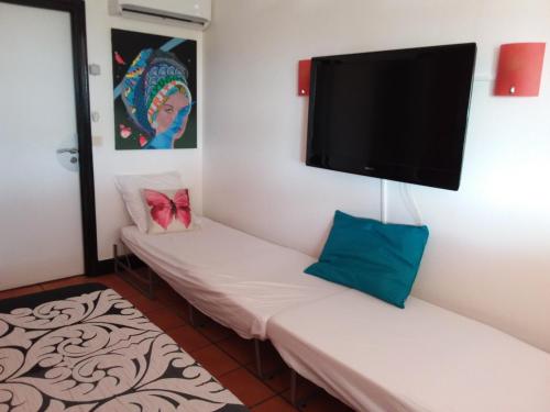 Cette chambre comprend 2 lits blancs et une télévision à écran plat. dans l'établissement Studio Vue mer Haut de villa anse des rochers, à Saint-François