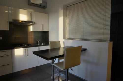 a kitchen with white cabinets and a black table and chairs at Villino Erminia - Seaside Art b&b in Pizzo