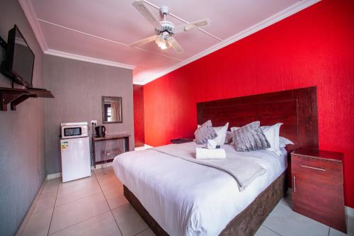 a bedroom with a large bed with a red wall at Khayalami Hotel - Standerton in Standerton