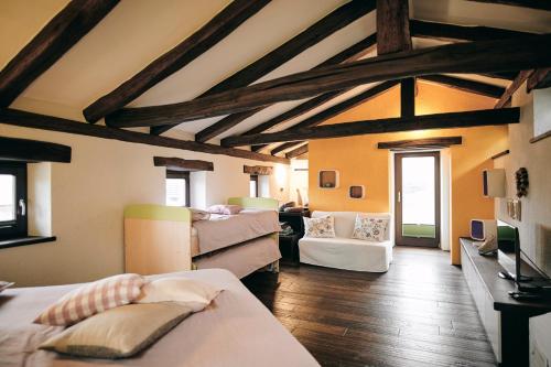 a room with beds and a living room with wooden ceilings at Tmbin's barn - nature, horses, family in Sežana