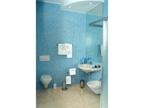 a blue tiled bathroom with a sink and a toilet at Hotel Royal in Vasto