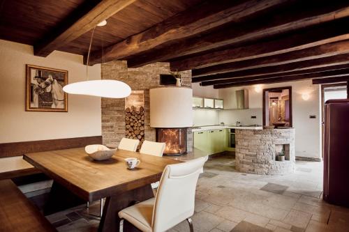 a dining room with a wooden table and a fireplace at Tmbin's barn - nature, horses, family in Sežana