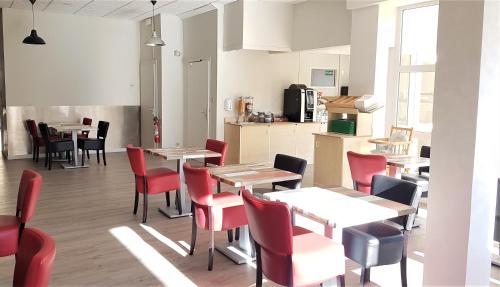 a restaurant with tables and chairs and a kitchen at Hôtel La Bérangère in Pérouges