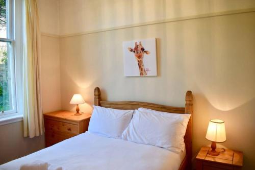 1 dormitorio con 1 cama blanca y 2 lámparas en Lovely Sunny 2 Bed Home Edinburgh Coast, en Edimburgo