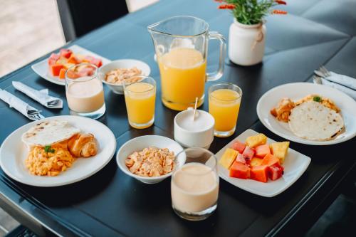una mesa con platos de comida y vasos de jugo de naranja en Tik by Bernalo Hotels, en Medellín