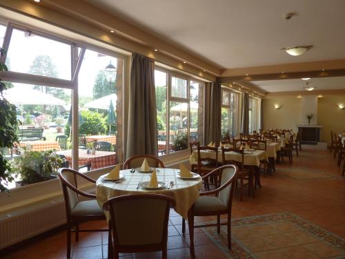 comedor con mesas y sillas y ventanas grandes en Zsanett Hotel, en Balatonkeresztúr