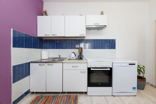 uma cozinha branca com armários brancos e um lavatório em Apartman Pandula em Tkon
