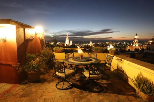 a table and chairs on a balcony with a view of the city at Casa Mia Suites in San Miguel de Allende