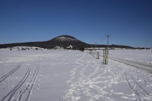 a snow covered road with a mountain in the background at Chata Lucie pod Řípem in Roudnice nad Labem